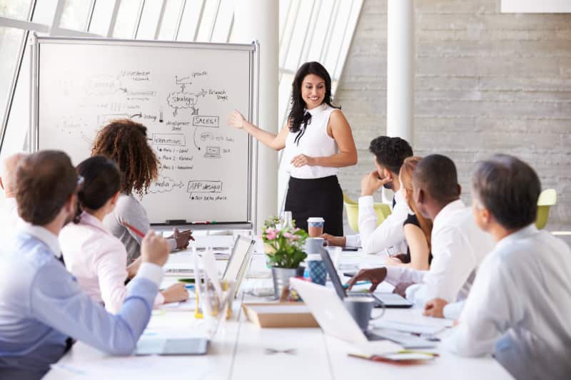 Woman presenting to people seated at a conference table